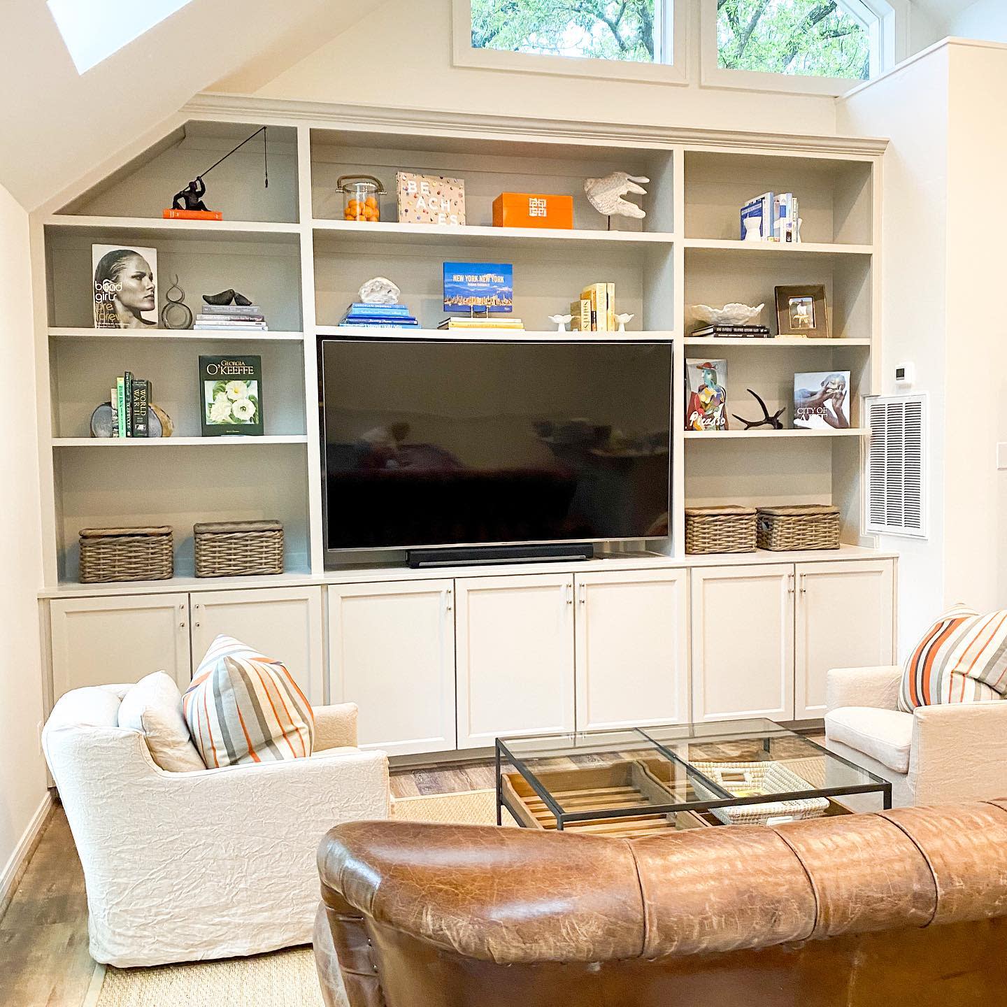 large recessed wall shelves and cupboards tan leather sofa lounge chairs glass table